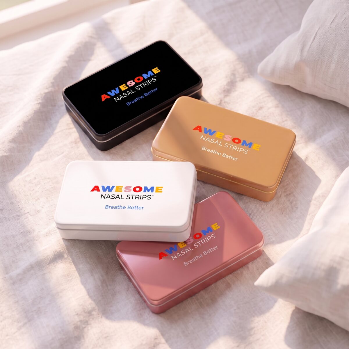 Awesome Nasal Strips tins in black, tan, white and pink on a bedsheet